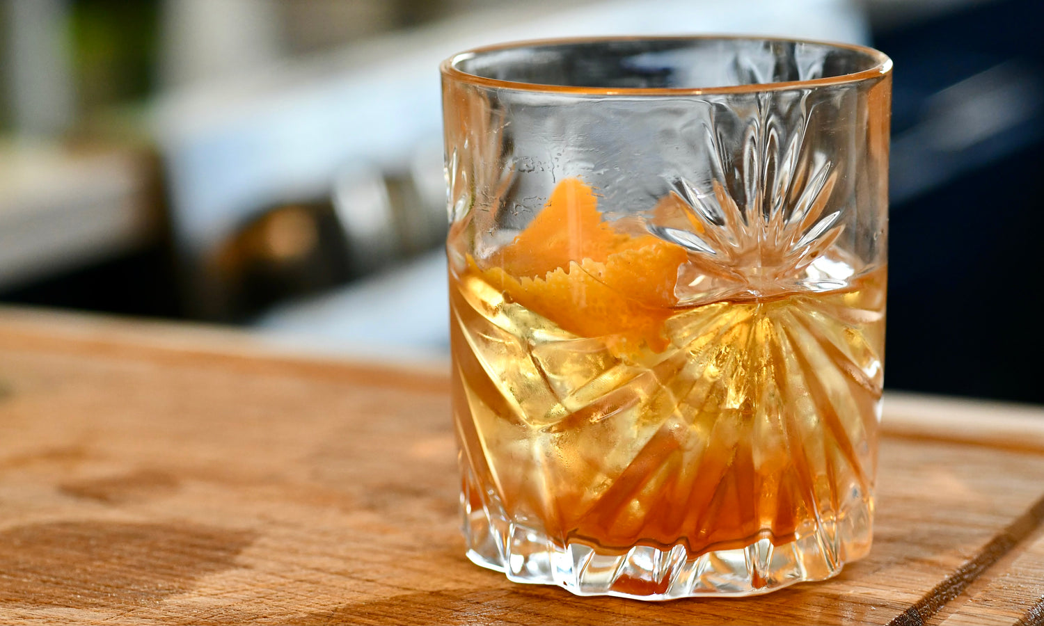 An Old Fashioned mixed cocktail in a crystal glass on a wooden board